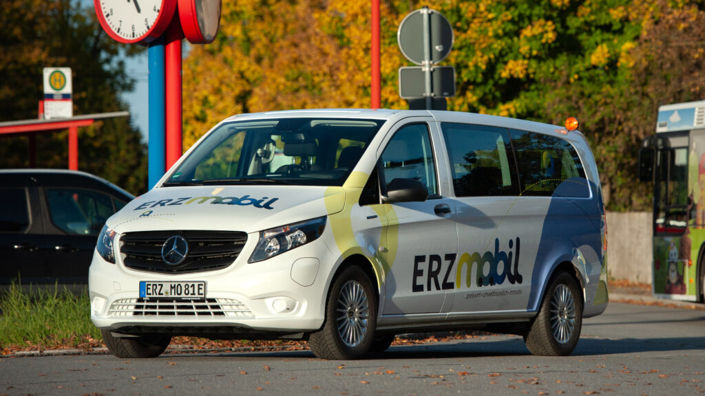 Ein weißer Bus mit der Aufschrift "Erzmobil" steht auf einer Straße