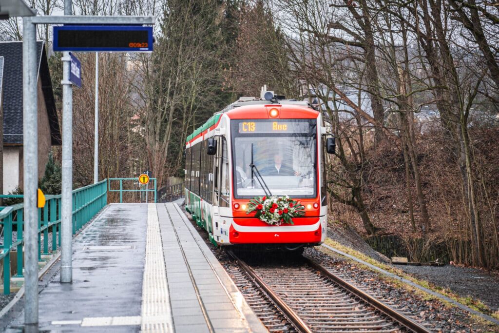 Die C13 fährt, mit einem Kranz geschmückt, an einem Haltepunkt ein