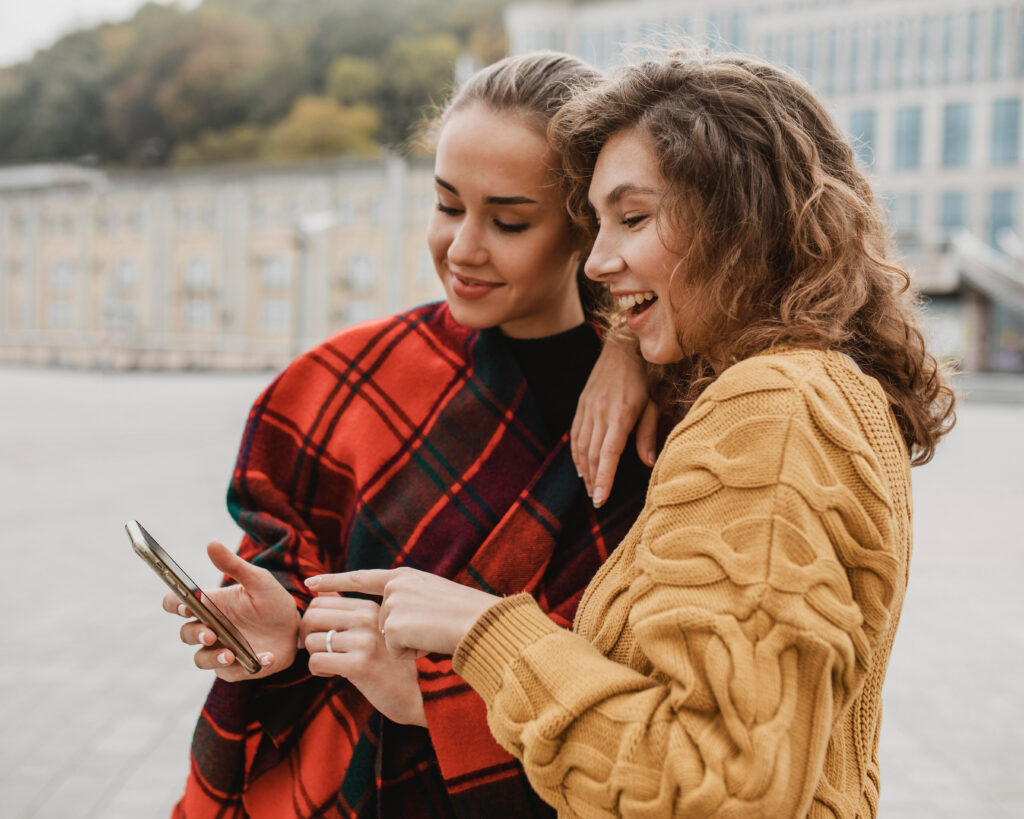 Zwei junge Frauen schauen lachend auf ein Smartphone