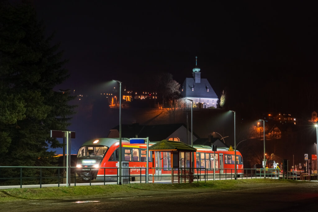 Olbernhau-Gruenthal im Advent - Zug vor beleuchteter Kirche bei Nacht.
