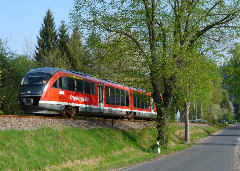 Die Flöhatalbahn fährt über einen grünen Bahndamm.