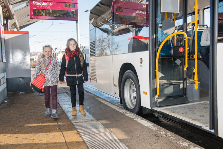 Zwei Mädchen laufen neben einem Bus