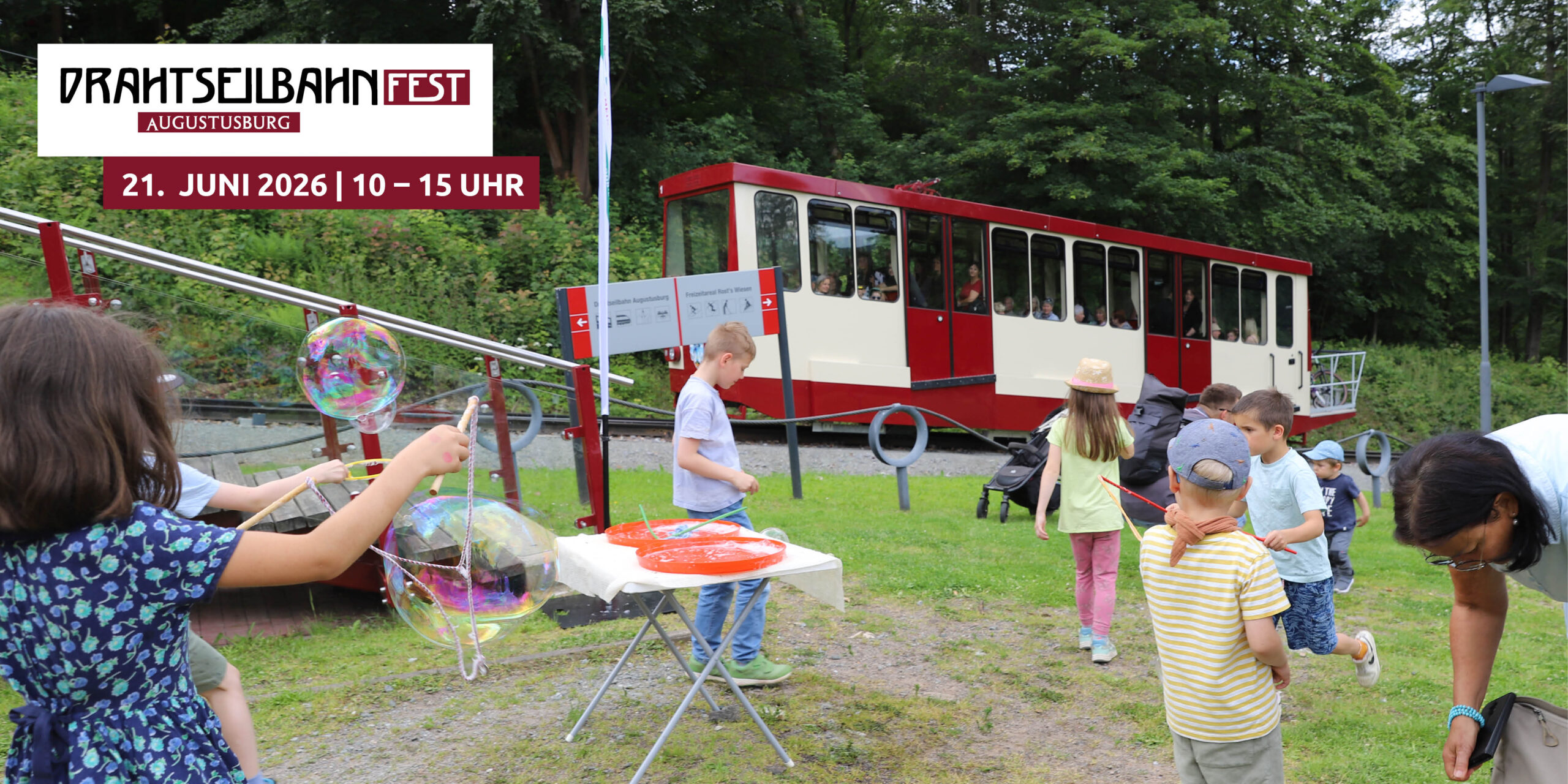 Kinder spielen am Seifenblasenspielplatz mit Drahtseilbahn Augustusburg im Hintergrund