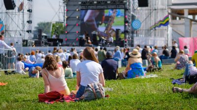 Viele Menschen sitzen im Gras mit vor großer Bühne