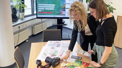 Zwei VMS-MItarbeiterinnen betrachten Printprodukte