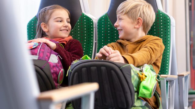 Zwei fröhliche Kinder sitzen in einem Citylink