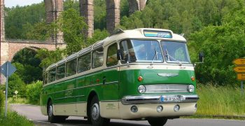 REGIOBUS Ikarus 55 (2022 04 08 06 30 09 UTC) Historischer Ikarus-Bus fährt auf Straße mit Viadukt im Hintergrund