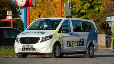 Ein weißer Bus mit der Aufschrift "Erzmobil" steht auf einer Straße