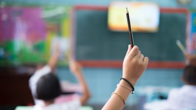 Student hands up asking a question in class at the elementary school. Education concept.